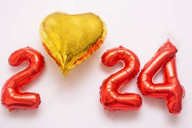 2024 kırmızı harflerle ve beyaz arka planda altın bir kalple yazılmış.