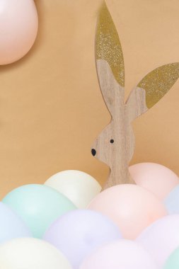 Bej arka planı ve yumuşak renkli topları olan paskalya tavşanı.