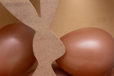 Bej arka planı ve çikolata renkli topları olan Paskalya tavşanı.