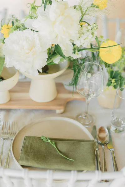Wedding table setting with linen napkin, ceramic plate and spring flowers. Trendy event design with earthy tones and natural materials. Bohemian style celebration decor.