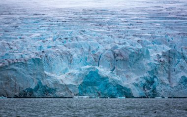 cruising in the Arctic in the Magdalensfjord on Svalbard along a glacier clipart