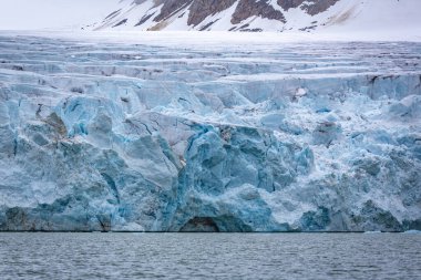 cruising in the Arctic in the Magdalensfjord on Svalbard along a glacier clipart