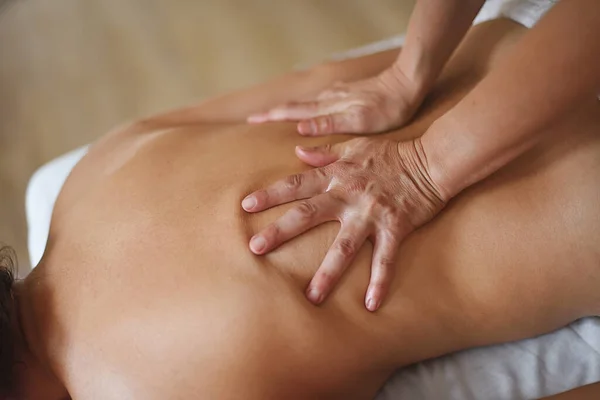 Professional masseuse giving oil massage in close-up on a woman's back, top view