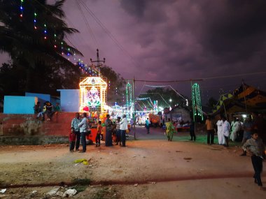 Mandya, Karnataka, Hindistan-Nisan 25, 2023: Kalamma Festivali sırasında bir Kadailavagilu köyünde güzel bir elektrik ışık dekorasyonunun kapatılması ve yanmış ağaç kömürü üzerinde yürüme.