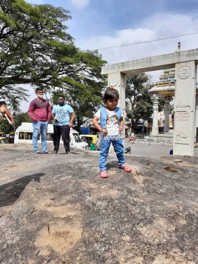 Bangalore, Karnataka, Hindistan-10 Ocak 2021: Gavi Gangadhareshwara Tapınağı yakınlarında kameraya farklı poz veren Hintli kız çocuğu.