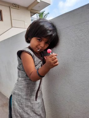 Bangalore, Karnataka, Hindistan-29 Mayıs 2021: Hintli kız çocuğu lolipop şeker tutuyor ve yiyor.