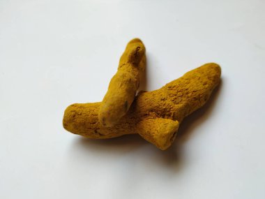 Beyaz bir arka planda izole edilmiş bir grup zerdeçal kökü. Zerdeçal, zerdeçal bitkisinden gelen bir baharattır. Genellikle Asya yemeklerinde kullanılır. Muhtemelen körinin ana baharatı olarak zerdeçal biliyorsunuzdur..