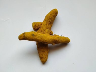 Beyaz bir arka planda izole edilmiş bir grup zerdeçal kökü. Zerdeçal, zerdeçal bitkisinden gelen bir baharattır. Genellikle Asya yemeklerinde kullanılır. Muhtemelen körinin ana baharatı olarak zerdeçal biliyorsunuzdur..