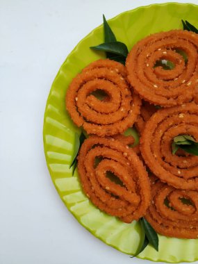 Group of Chakli in a Green Plate isolated on White Background. Indian Snack Chakli or chakali made from deep frying portions of a lentil flour dough clipart