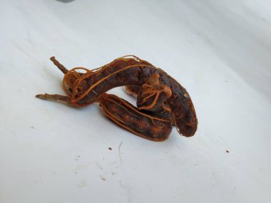 Tropikal demirhindi meyvesine yakın çekim. Kabuğu olmadan soyulmuş, görünür tohumlar ve iç posası var. Beyaz arkaplanda izole