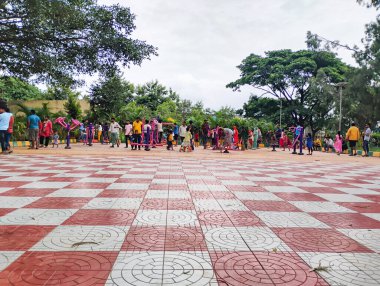 Bangalore, Karnataka, Hindistan-7 Temmuz 2024: Kamu gençleri ve yaşlılarının parkta spor aletleri ve doğa arka planında çalışmaları.