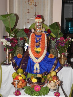 Bangalore, Karnataka, Hindistan-25 Ağustos 2023: Festival sırasında farklı türde çiçek ve meyvelerle Tanrıça Vara Mahalakshimi heykelinin veya kalaşın güzel puja süslemesi.