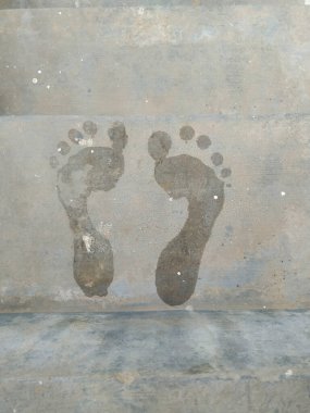 Closeup of young lady wet feet and foot symbol before its dry in a floor. clipart