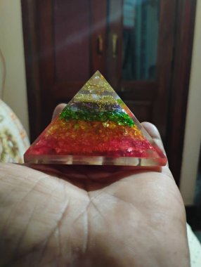 Closeup of colorful glass vastu pyramid holding in a hand. clipart