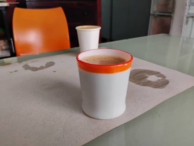 Ofisin arka planındaki güzel doldurulmuş kağıt ve seramik kahve fincanının yakın çekimi..