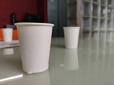 Ofisin arka planındaki güzel doldurulmuş kağıt ve seramik kahve fincanının yakın çekimi..