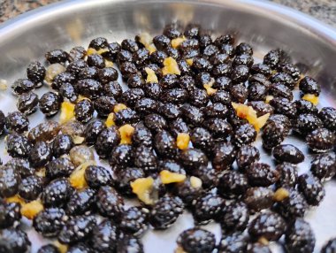 Çelik bir plaka ve tohum dokusu arka planında papaya meyvesi yığınının güzel siyah tohumlarının yakın çekimi.