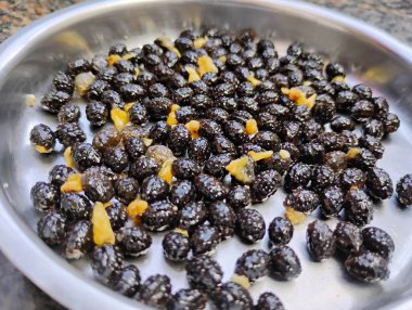 Çelik bir plaka ve tohum dokusu arka planında papaya meyvesi yığınının güzel siyah tohumlarının yakın çekimi.