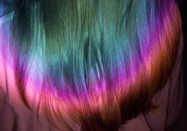 Rainbow light reflecting on long blonde hair. Party look. Or a new topping? Long and colorful hair in shades of the rainbow spectrum.