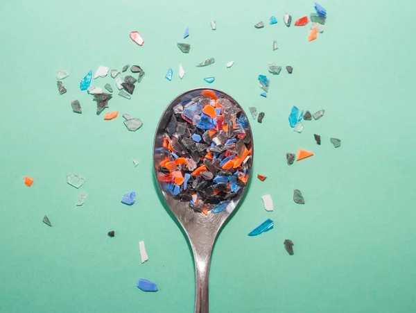 塑料制品及其部件压垮了整个地球 勺子里装满了五彩斑斓的小塑料碎片 — 图库照片
