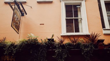 Londra, İngiltere - 25 Mart 2025: Soho 'daki Eski Kahve Evi' nin asılma tabelası ve üst cephesi, saksı bitkileri ve klasik ayrıntılarla dolu.