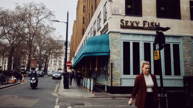 Londra, İngiltere - 25 Mart 2025: Mayfair, Londra 'da Bruton Lane' deki Seksi Balık Restoranı girişi yayalar ve trafik manzaralı.