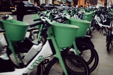 Londra, İngiltere - 25 Mart 2025: Lime elektrikli bisikletlerden oluşan büyük bir grup, sürdürülebilir kentsel taşımacılığı desteklemek için Mayfair, Londra 'da kaldırım boyunca dizildiler.