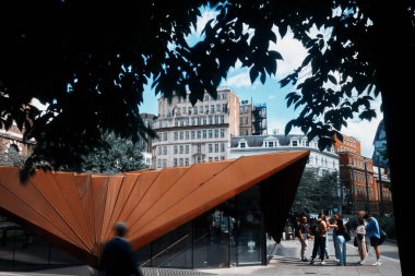 Londra, İngiltere - 28 Eylül 2024: İnsanlar Londra şehrindeki modern bir mimari pavyonun yanında Aldgate Tap 'in dışında toplanıyor..