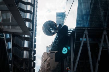Londra, İngiltere - 28 Eylül 2024: Londra şehrinde cam ve çelik binalarla çerçevelenmiş, sokak manzaralı yeşil bir trafik lambası.