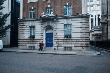 Londra, İngiltere - 28 Eylül 2024: Yayalar, canlı mavi bir kapı ve armanın yer aldığı Londra 'nın tarihi ahır koridorlarından biri olan Wax Chandlers Hall' un yanından geçtiler