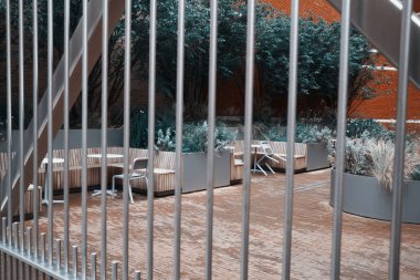 Londra, İngiltere - 28 Eylül 2024: Londra City 'deki dikey barlardan bakıldığında modern bir avluda ahşap banklar ve ekiciler.