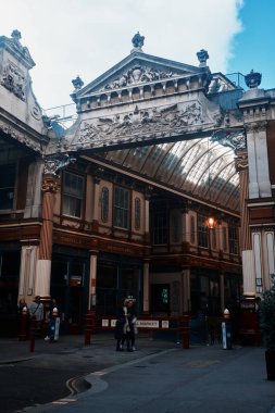 Londra, İngiltere - 28 Eylül 2024: İnsanlar Londra 'nın kalbinde bulunan tarihi Viktorya dönemi atari salonu Leadenhall Market' in dekoratif taş pedikürünün altında yürüyor.