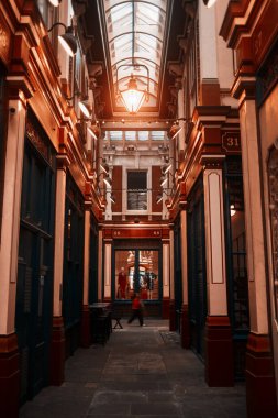 Londra, İngiltere - 28 Eylül 2024: Leadenhall Market 'te bir koridorda yürüyen insanlar, klasik ışıklandırma ve moda mankenleri sergileniyor.
