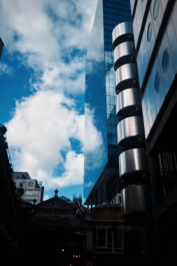 Londra, İngiltere - 28 Eylül 2024: Londra 'nın finans bölgesinde Lloyds Building ve Leadenhall Market yakınlarındaki bulutların yansımaları ve mimari karşıtlık