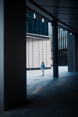 Londra, İngiltere - 28 Eylül 2024: Gölgeli bir mimari geçit Londra şehrindeki modern ofis binalarıyla çevrili minimalist bir taş avluya açılıyor.
