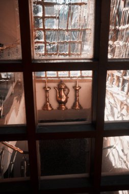 Londra, İngiltere - 28 Eylül 2024: Londra şehrinde ışık ve detayı yansıtan, tarihi bir pencerenin eski, dalgalı camlarından görülen ılık tonlu pirinç nesneler.