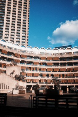 Londra, İngiltere - 28 Eylül 2024: Kıvrımlı beton balkonlarda güneş parlıyor ve Londra 'nın merkezindeki Barbican Malikanesi' ndeki Gilbert Evi 'nin yemyeşil ekili terasında..