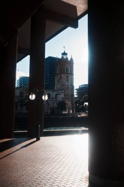 Londra, İngiltere - 28 Eylül 2024: St. Giles 'sız Cripplegate Kilisesi modern binalar arasında gölün ötesine geçerken Barbican terası boyunca öğleden sonra ışığı taştı.