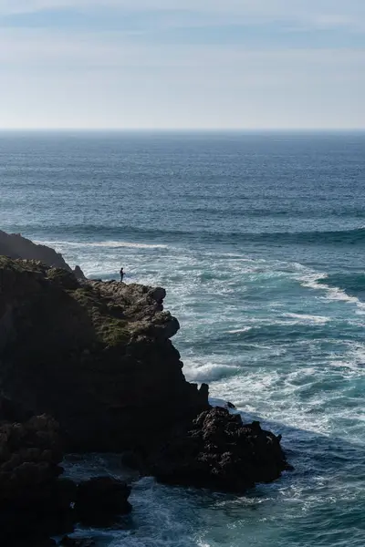 Okyanus kıyısındaki bir uçurumda balıkçı.