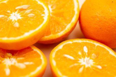 Pembe arka planda portakallar. Portakallardan biri ortadan ikiye bölünmüş, diğeri ise tek parça..