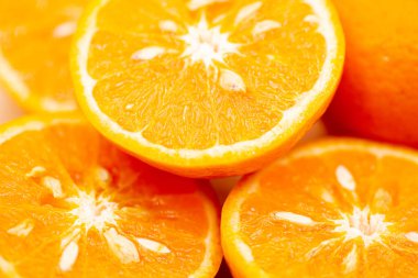 Pembe arka planda portakallar. Portakallardan biri ortadan ikiye bölünmüş, diğeri ise tek parça..