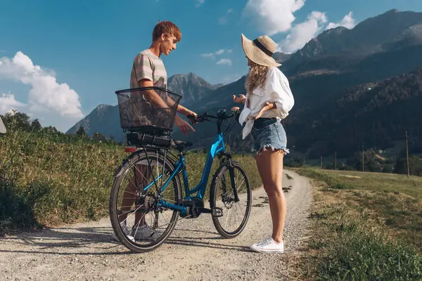 两个朋友或夫妇正在沿路骑车 运动和积极生活的日落时间概念 情侣们学习骑自行车 一起玩乐 在城市附近的山上旅行 图库图片
