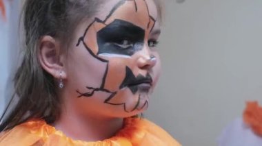 Cadılar Bayramı kostümü giymiş bir çocuk kameraya dönüp gülümsüyor. 