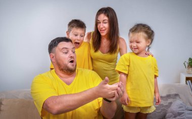 Bir aile portresi, baba elinde bir şey gösteriyor ve aile şaşırmış görünüyor.