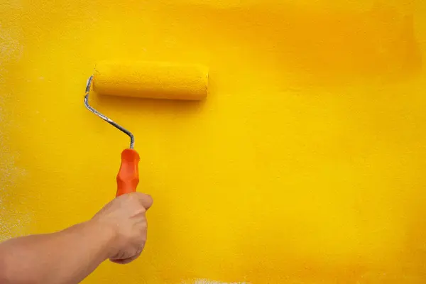 Sarı boyalı bir duvarı tamir rulosu kullanarak boyamak.