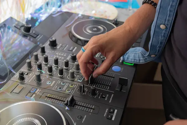 DJ profesyonel bir ses karıştırıcının kontrollerini ayarlıyor, canlı müzik performansı veya etkinliği için hazırlanıyor.