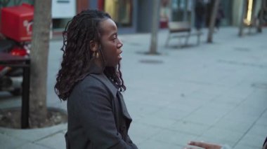 İki neşeli genç kadın, bir şehir caddesinde birlikte gülüp eğleniyorlar.