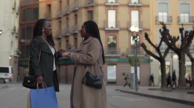 İki bayan arkadaş alışveriş çılgınlığından sonra dışarıda bir şeyler atıştırıyor.