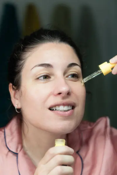 Kafkasyalı kadın günlük cilt bakımı için kozmetik serumu kullanıyor.