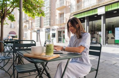 İş kadını dışarıda bir kafede laptopuyla çalışırken sağlıklı bir kahvaltı yapıyor.